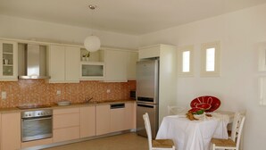 Eine moderne Küche mit weißen Schränken, einem Edelstahl-Kühlschrank und einem Esstisch mit Stühlen.