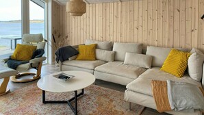 Una sala de estar acogedora con sofá, sillón y mesa de centro, paredes de paneles de madera y vistas al exterior.