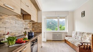 Una cucina con zoccolo in pietra, mobili in legno, un fornello e una finestra vista verde.