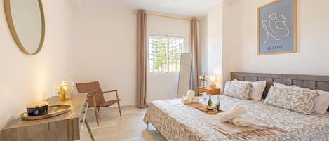 Une chambre à coucher comprenant un lit, un bureau, une chaise, un ventilateur de plafond et une fenêtre avec des rideaux.