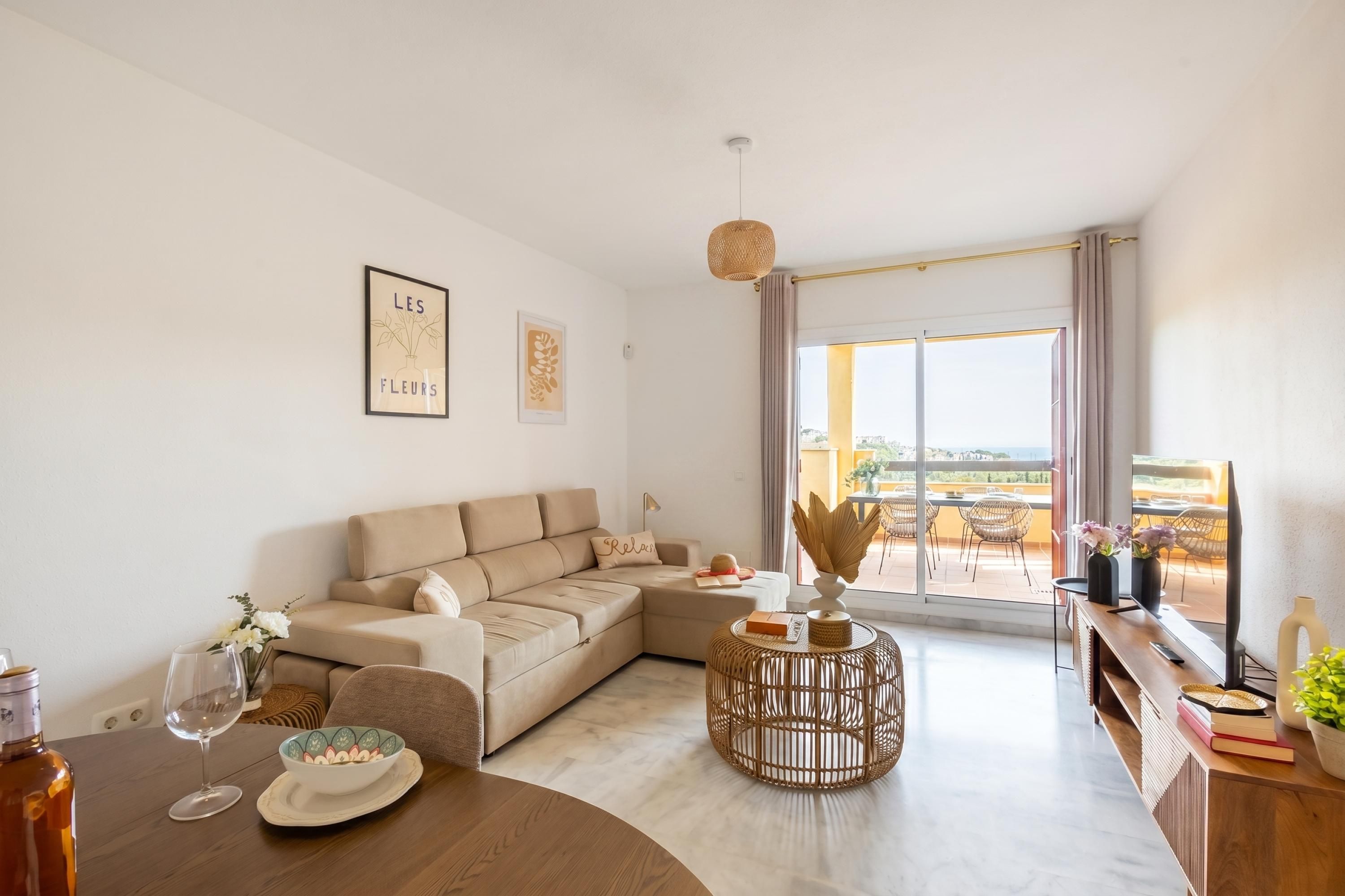 A modern living room with a sofa, a round coffee table, and a dining table with a wine glass.