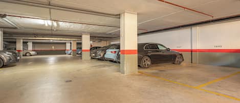 Un estacionamiento subterráneo de varios niveles con pisos de concreto, pilares y espacios de estacionamiento delimitados.