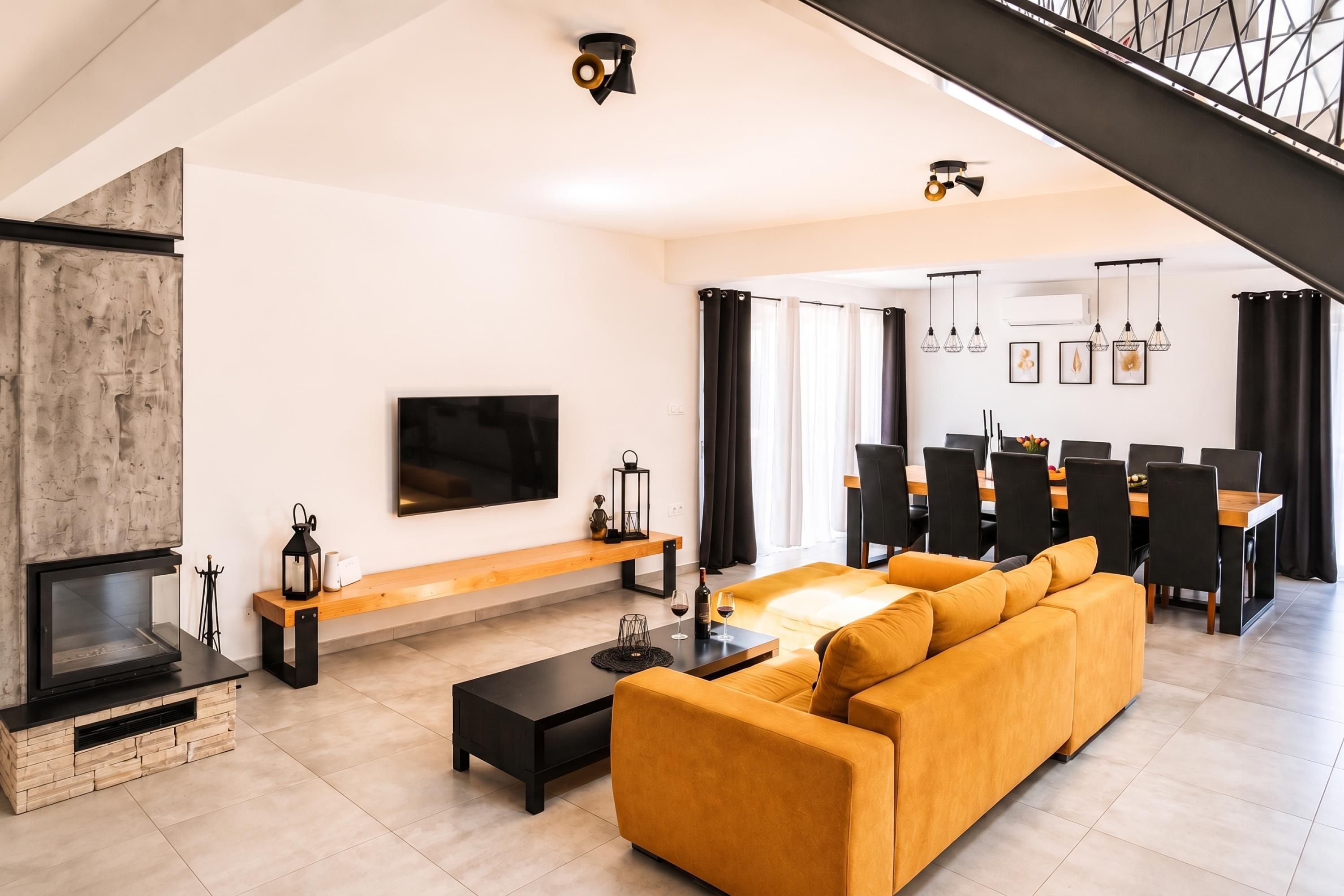 Een moderne woonkamer met een open haard, een bank, een salontafel en een eethoek met stoelen en een tafel.