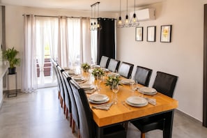 A dining area with a long table set for six, black chairs, and a potted plant. - Villa Anastazija Family Retreat With Pool (Sveta Nedelja)