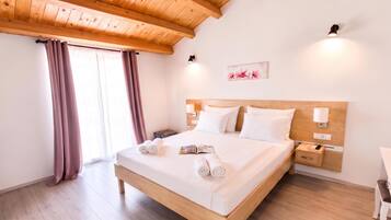 Quarto de hotel com teto de madeira, cama com roupa de cama branca, mesa de cabeceira e luminária fixada na parede.