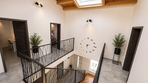 Ein mehrgeschossiges Interieur mit Oberlichter, einer Wanduhr und Zimmerpflanzen.