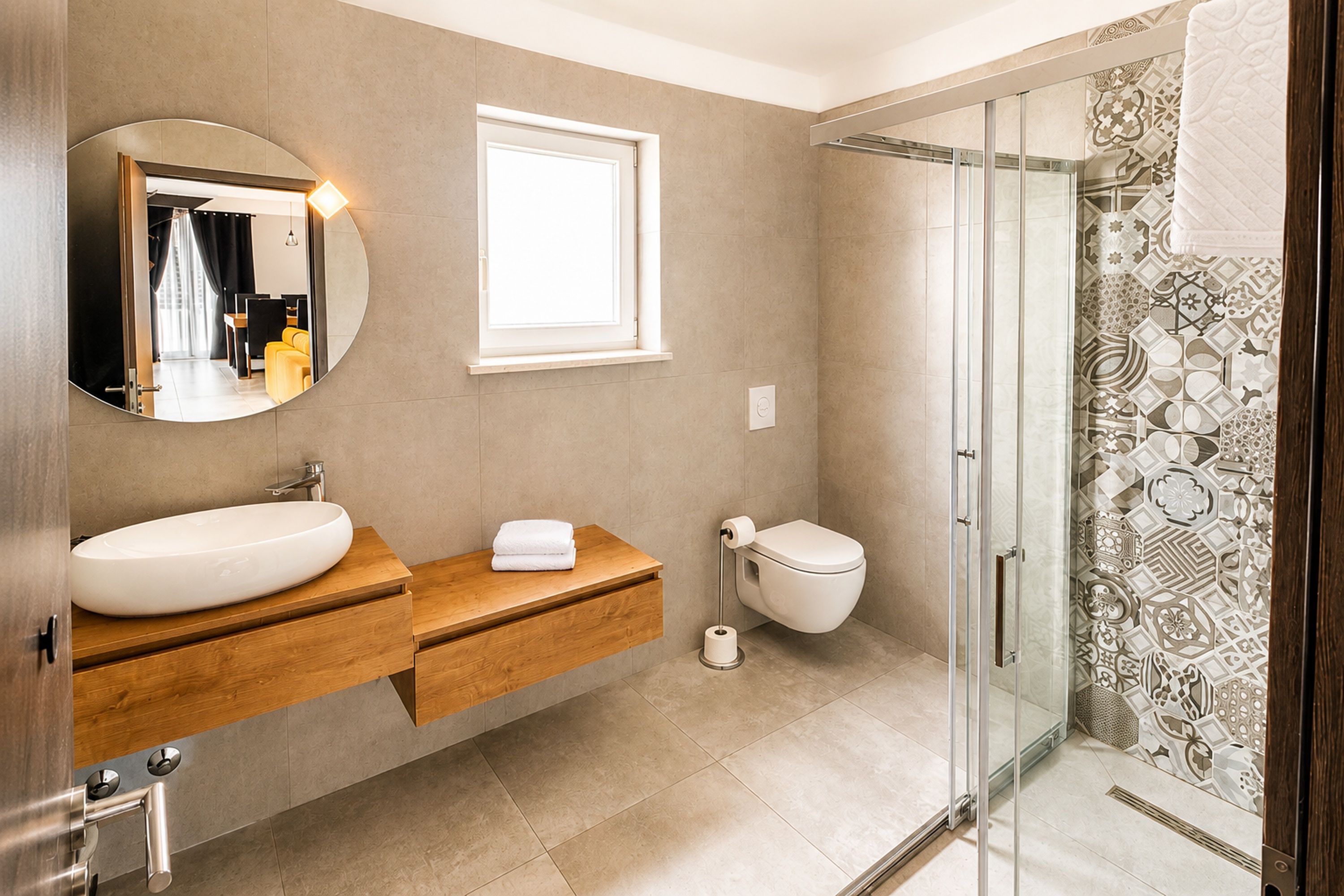 A modern bathroom with a large mirror, a sink, a toilet, and a glass-enclosed shower.