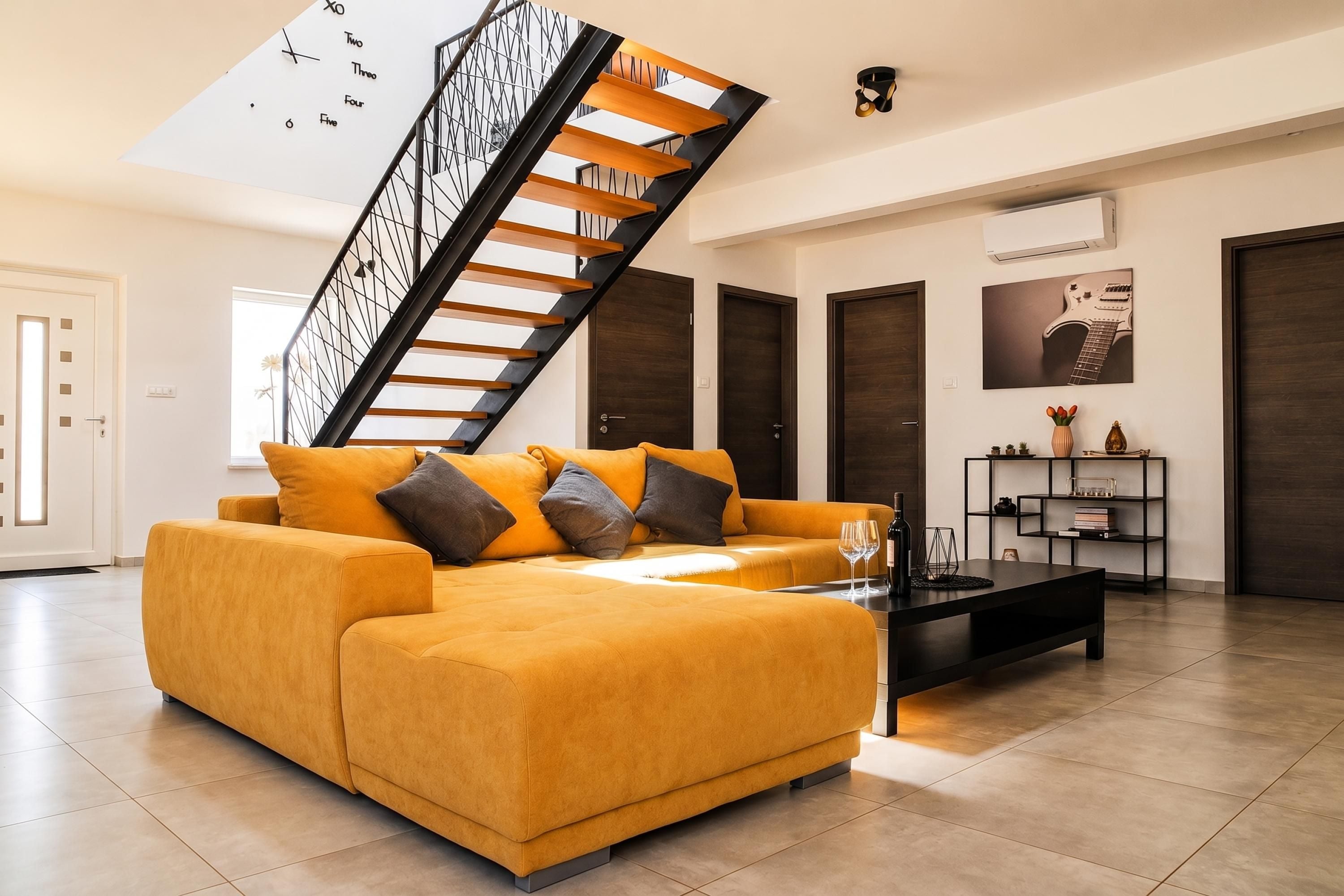 Sala de estar moderna com sofá, mesa de centro e escada.