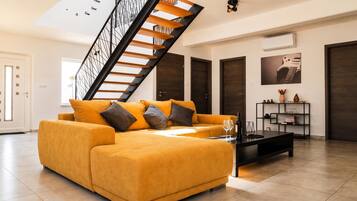 Sala de estar moderna com sofá, mesa de centro e escada.