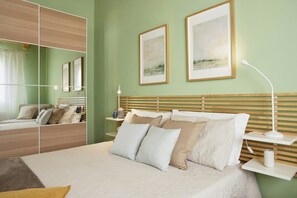 Ein ordentlich eingerichtetes Schlafzimmer mit Bett, Nachttischen, einem Spiegel und Bildern an der Wand.