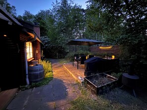 A patio area with a grill, outdoor seating, and a wooden deck.