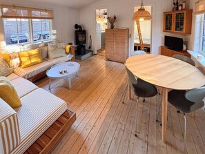 A cozy living room with a sofa, a round coffee table, a dining table with chairs, a fireplace, and a kitchen area.