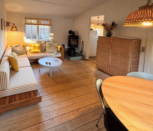 A cozy living room with a sofa, a round coffee table, and a dining table.