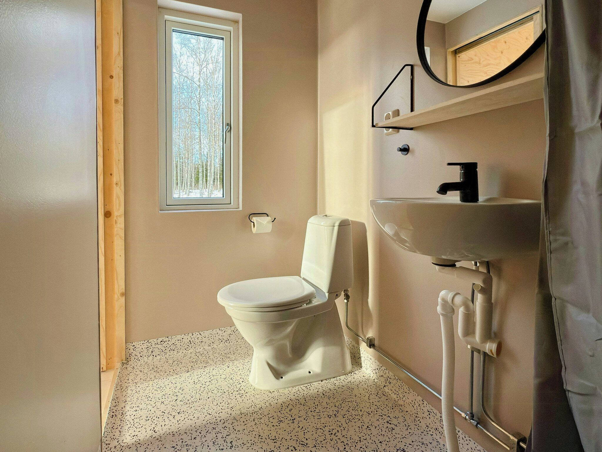Et badeværelse med toilet, håndvask og et vindue.