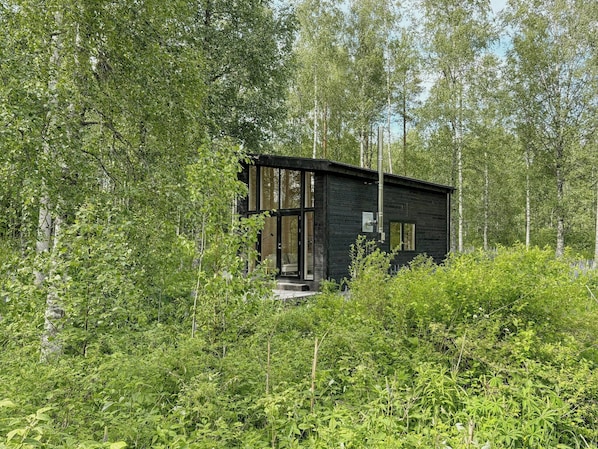 Eine moderne Holzhütte, umgeben von dichtem Wald.