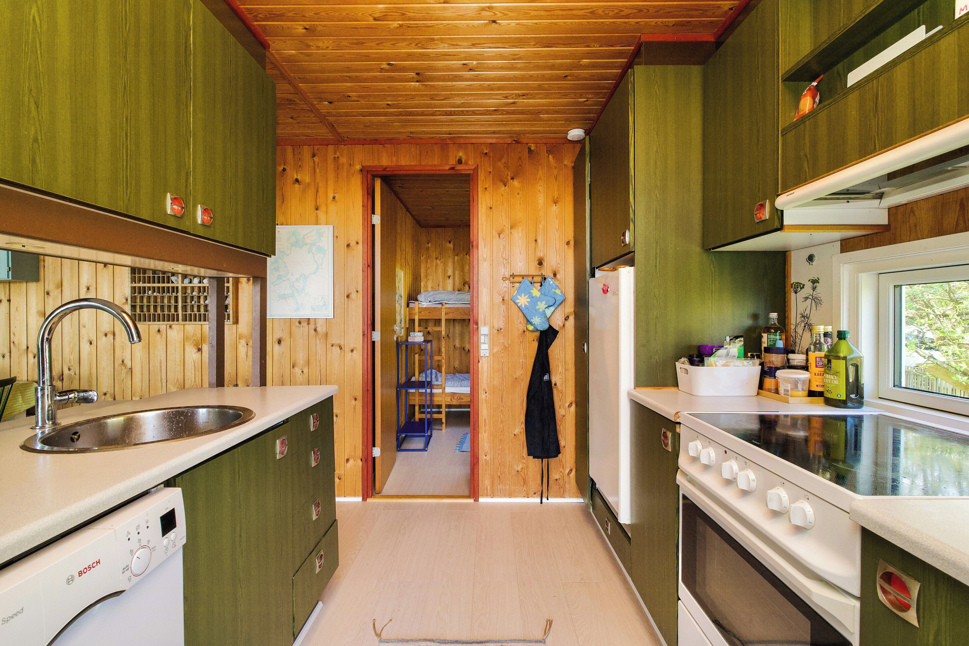 A kitchen with wooden walls, a Bosch dishwasher, a stove, and a window.