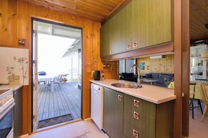 Eine kleine Küche mit Holzschränken, einem eingebauten Geschirrspüler und einer Arbeitsplatte.