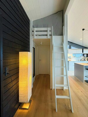 Un intérieur moderne avec une chambre en mezzanine, un escalier et un espace cuisine.