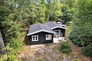 Una casa nera con veranda, immersa in una fitta foresta.