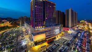 Un hôtel à plusieurs étages, doté d’une enseigne bien visible, d’un parking et entouré d’immeubles de grande hauteur.