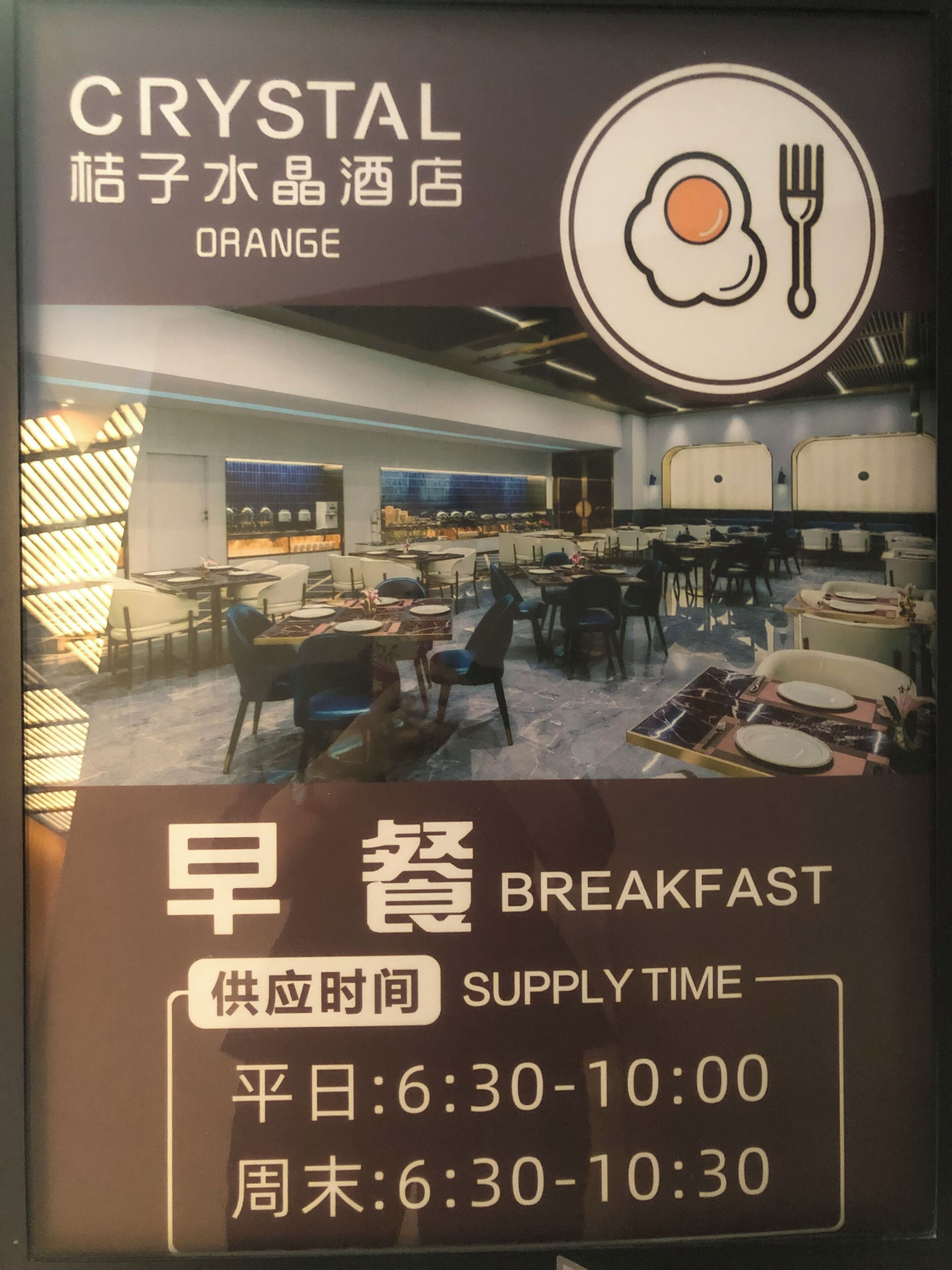 Ein Restaurantinneres mit Tischen, Stühlen und einer Tafel, die die Frühstückszeiten anzeigt.