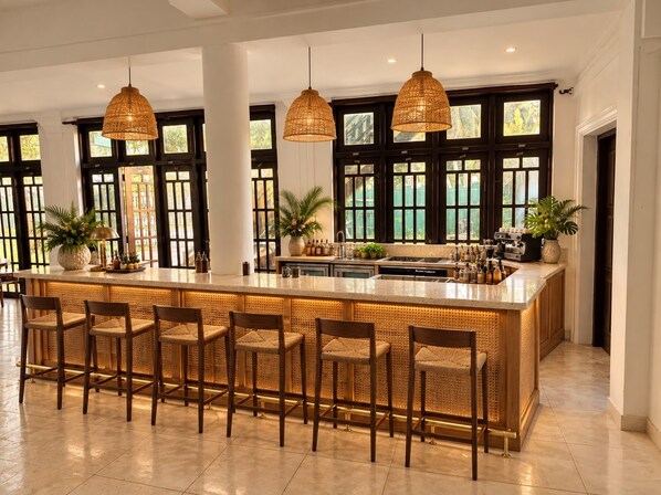 A spacious kitchen with a central island, bar stools, pendant lighting, and large windows. - Dimora Ceylon (Dikwella)