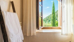 Ein Badezimmer mit großem Fenster, Handtuchhalter und Blick auf eine grüne Landschaft.