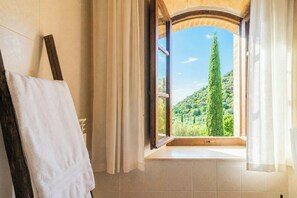 A bathroom with a large window, a towel rack, and a view of a green landscape. - Private pool villa on wine estate near Montalcino (Grosseto)
