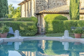 A stone building with a pool, surrounded by well-maintained hedges and potted plants. - Private pool villa on wine estate near Montalcino (Grosseto)