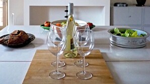 Een eettafel met wijnglazen, een fles en een houten plank.