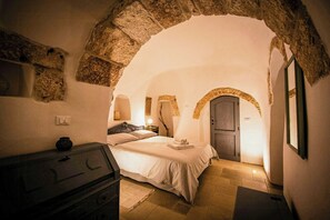Ein Schlafzimmer mit einem steinernen Bogen, einem Bett, einem Schminktisch und einer Tür.