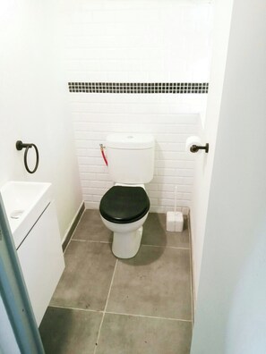 Une petite salle de bain avec des toilettes, un lavabo et un sol carrelé.
