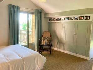 Une chambre à coucher avec un lit, une chaise, une armoire et un balcon.