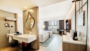 A modern hotel room with a large bathroom vanity, a bed, a desk, and a large mirror.