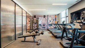 A gym with treadmills, weight machines, and a wall mural.