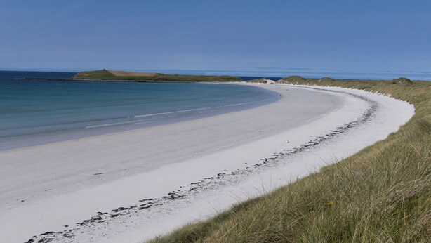 Una playa con arena y dunas cubiertas de hierba.