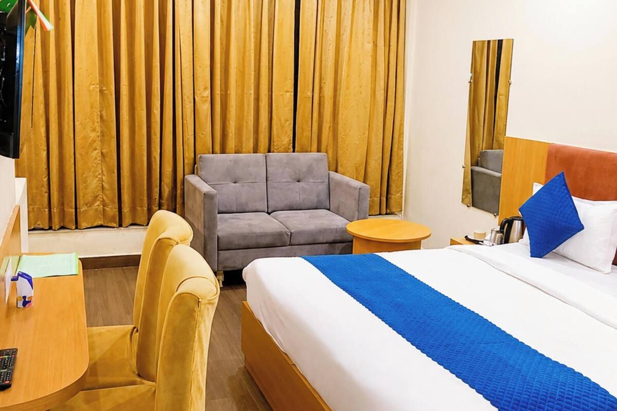 Una habitación de hotel con cama, sofá, escritorio y silla.