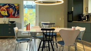 Un espace repas moderne avec une table ronde, des chaises noires et un luminaire suspendu.