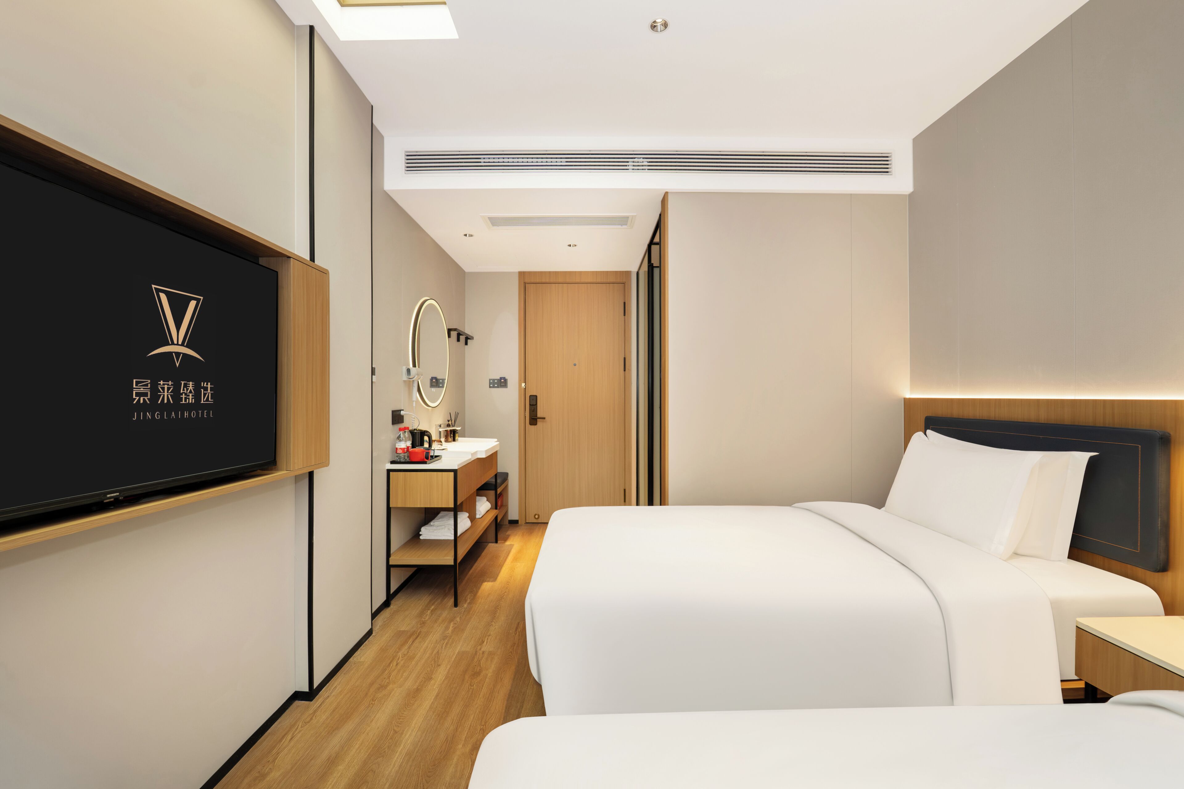 A hotel room with a bed, bedside table, and a wall-mounted TV displaying the hotel logo.