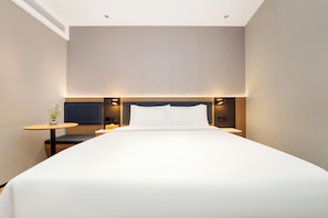 Una habitación de hotel moderna con una cama grande, mesitas de noche y un televisor de pantalla plana.