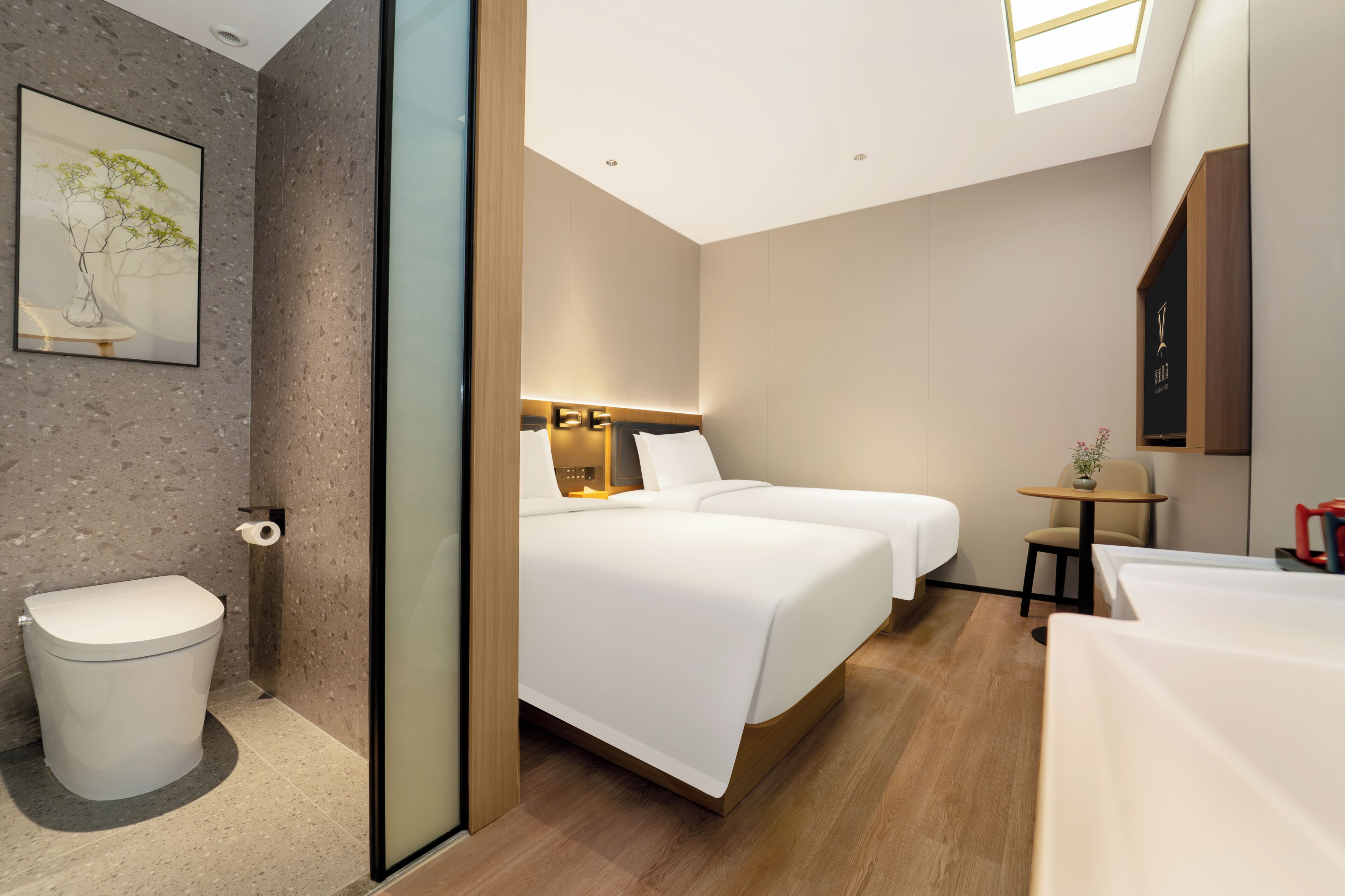 A modern hotel room with a large bed, a small bedside table, a toilet, and a shower area.