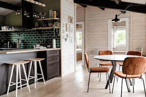 A modern kitchen with a bar area, wooden flooring, and a dining set with chairs. - Sea view and relaxation in Mols Hills (Rønde)