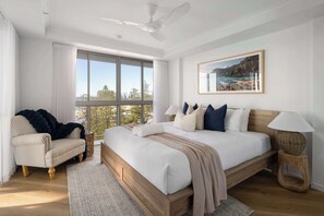 Ein Schlafzimmer mit einem großen Bett, einem Sessel, einer Stehlampe und Blick ins Freie.
