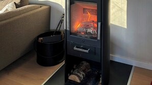 En moderne stue med en brændeovn, en sofa og en dekorativ vægdekoration.