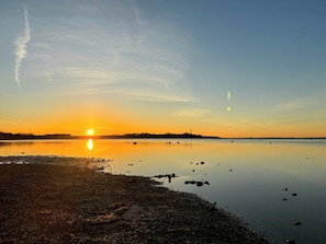 Un lago tranquillo al tramonto con cielo sereno, acque calme e una costa lontana.