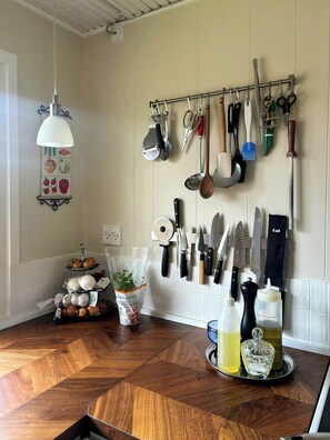 Una cucina con un espositore pensile per utensili, un tagliere in legno e un sacco di cipolle.