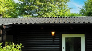 En lille hytte med en hvid dør, et vindue og en lampe over døren.
