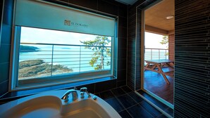 Un baño con un ventanal grande, una bañera y vistas al mar.