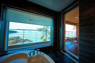 Un baño con un ventanal grande, una bañera y vistas al mar.