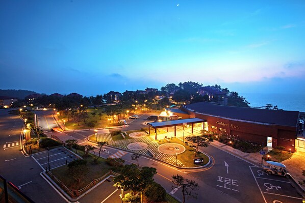 A hotel with a roundabout, parking area, and a view of the sea.